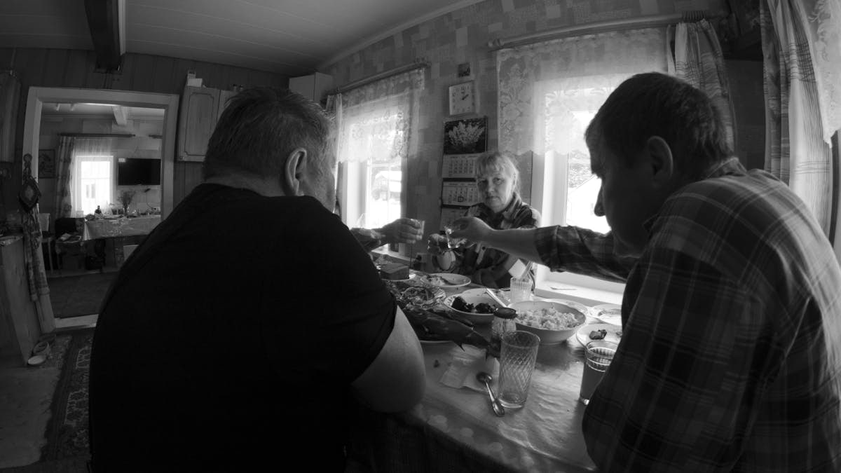Monochrome scene of family toasting indoors around a table, evoking warmth and togetherness.